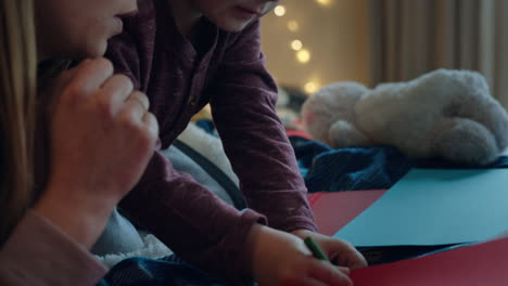 niño pequeño haciendo invitaciones para la fiesta de cumpleaños con la madre ayudando al hijo en el dormitorio colorido disfrutando de la imaginación creativa