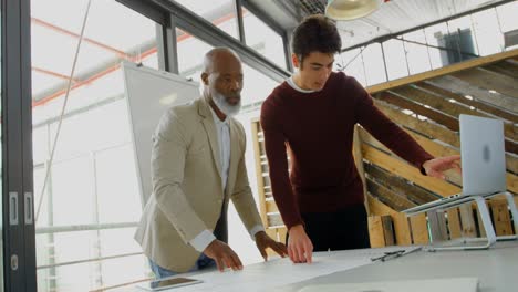 executives discussing over laptop and blueprint in the office 4k