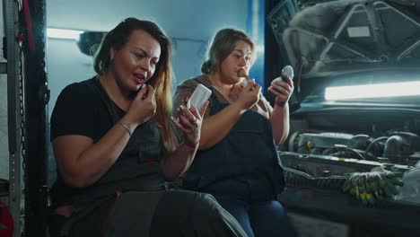 women mechanics applying makeup in a garage