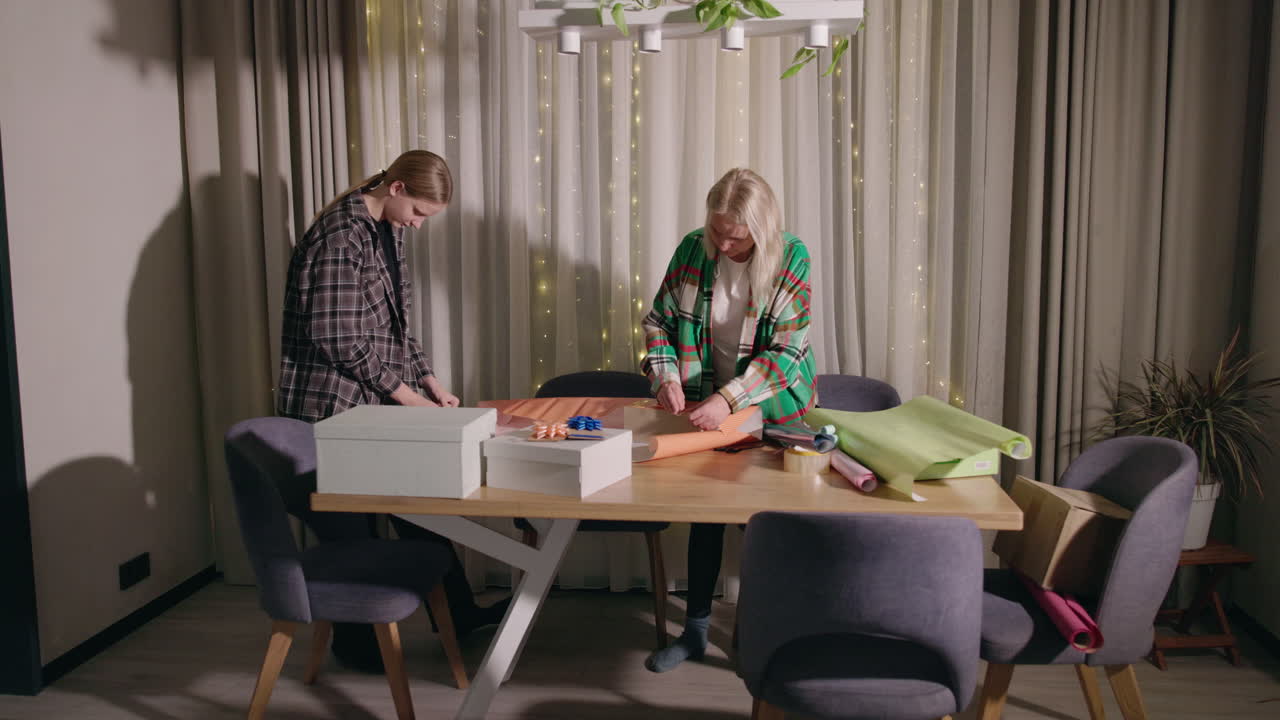 어머니 와 딸 이 크리스마스 선물 을 포장 하고 있다