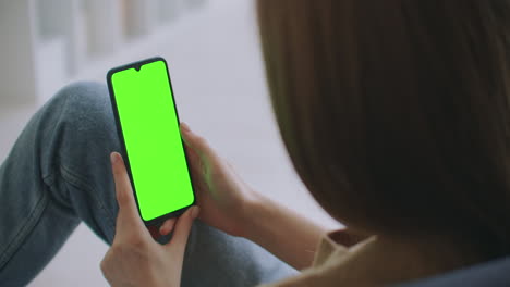 Close-up-shot-of-green-screen-template-smartphone-in-female-hands-at-home-girl-is-watching-content-without-touching-gadget-screen.-Modern-technology-and-information-concept.