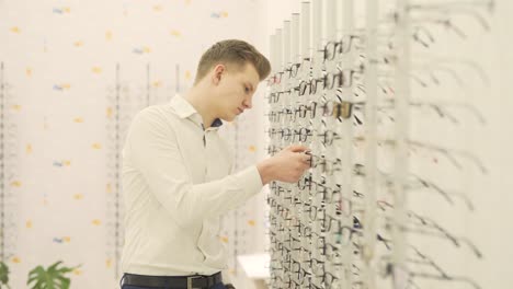 guy trying to choose a pair of eyeglasses in an optical shop