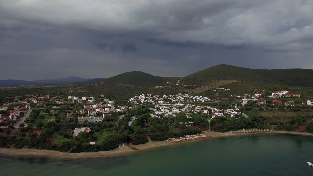 volando sobre la playa y las cabañas en la ciudad turística de grecia en un día nublado