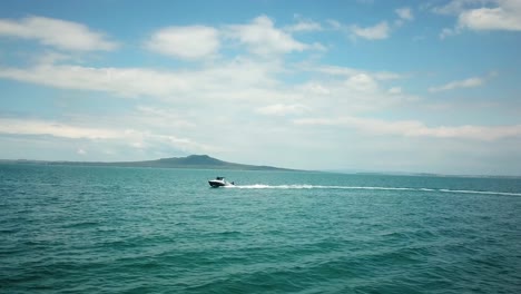 Luftaufnahme-Eines-Schnellboots,-Das-Seitlich-Mit-Der-Insel-Rangitoto-Im-Hintergrund-In-Neuseeland-Unterwegs-Ist