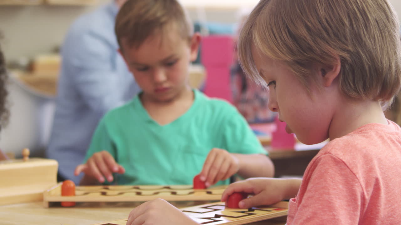 Aluno Montessori trabalhando na mesa com quebra-cabeça de formas de madeira