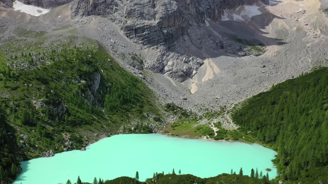 Lake Sorapis bright turqoise water in the Dolomites Italy, tilt up aerial