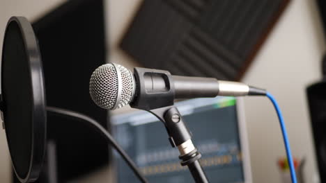 un micrófono vocal y un filtro antipop para cantar o grabar un podcast en un estudio de música de dormitorio desliza hacia la izquierda