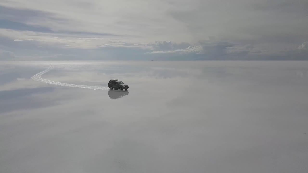 반사와 함께 볼리비아의 소금 평지 살라 데 우유니에서 차량의 무인 항공기 공중 샷