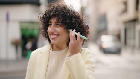 young woman smiling confident listening audio message by the smartphone at street