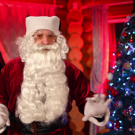 portrait of santa claus indoors. aged man in santa claus costume with natural beard congratulations with christmas. elderly man talking on camera wishing merry christmas