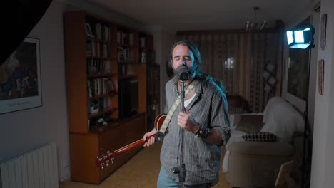 man singing and playing acoustic guitar at home