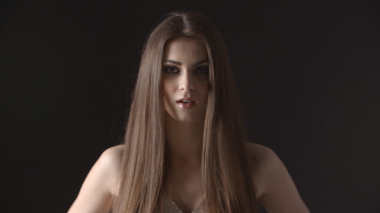 una mujer joven camina hacia la cámara, se enfoca, mueve el cabello, sonríe.