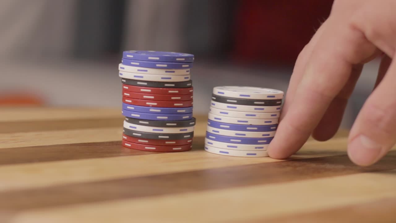 static of a man slowly pushing poker chips to another stack