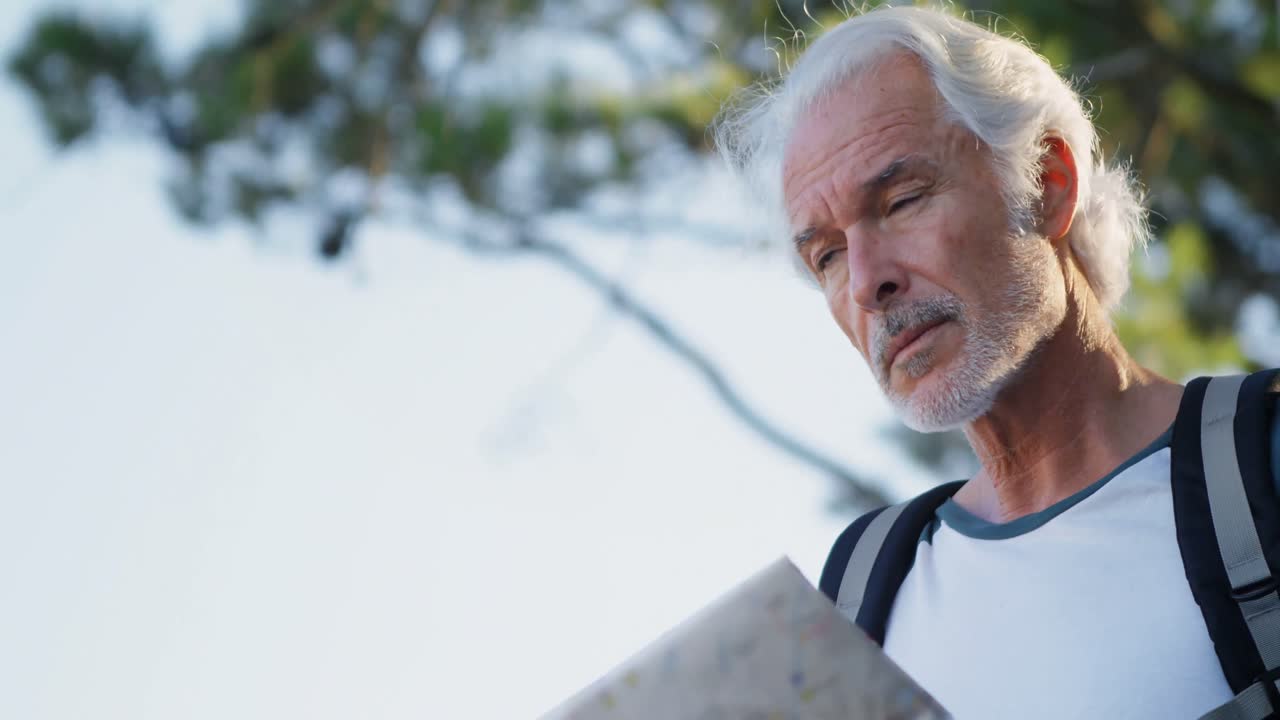 Senior man looking at map in the forest 4k