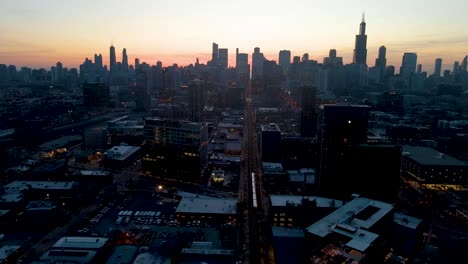 Una-Cautivadora-Vista-Aérea-De-Un-Drone-De-Chicago-Al-Anochecer,-Mostrando-Rascacielos-Iluminados-Contra-El-Cielo-Cada-Vez-Más-Oscuro,-Los-Tonos-Dorados-Del-Atardecer-Pintan-Un-Telón-De-Fondo-Sereno,-Destacando-Maravillas-Arquitectónicas