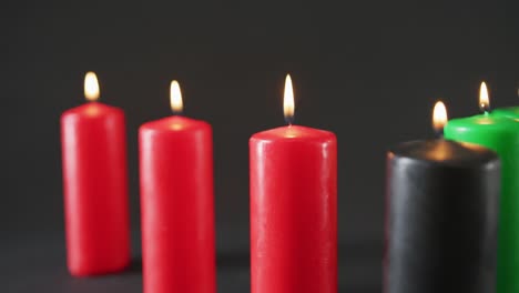 composición de velas verdes, negras y rojas encendidas de halloween contra un fondo negro