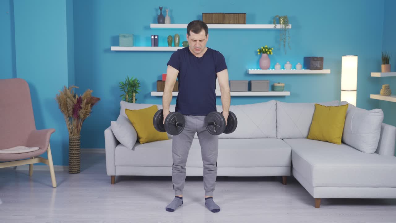 약하고 경험이 없는 남자가 집에서 장비를 가지고 운동하고 있습니다.