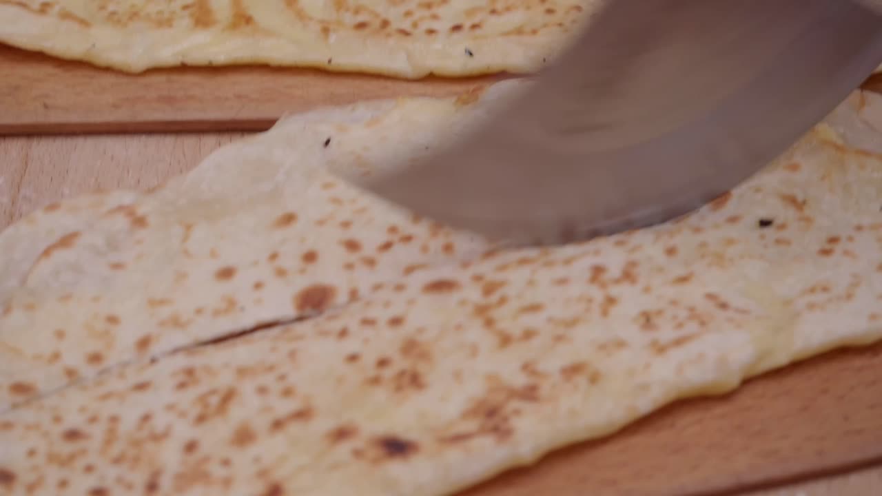 Gözleme being cut on a wooden board