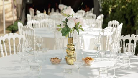 mesa de bodas con vino de vidrio claro y un jarrón de oro para la pieza central
