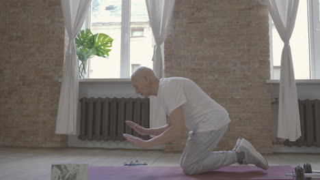 old man stretching and exercising on yoga mat at home