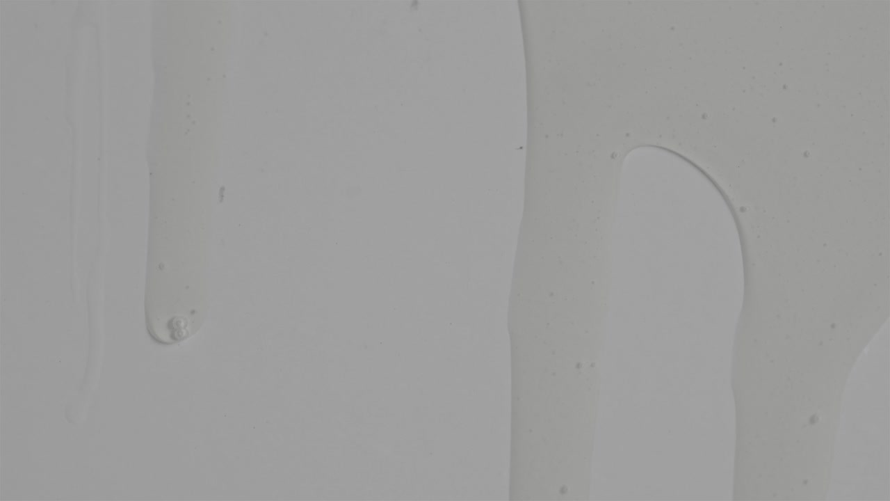 líquido claro espeso y suave deslizándose sobre una superficie plana blanca