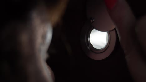 worried woman looking through the peephole in theevening, eye close-up