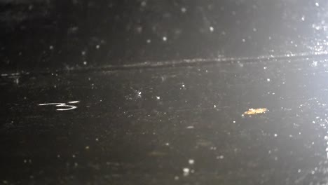 raindrops falling on a lit street at night, slow motion.