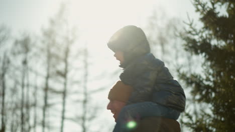 a close up of a father playing with his son he is carrying on his shoulders with light reflection seen on them