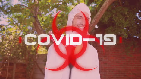 la palabra covid-19 escrita sobre un cartel de peligro para la salud con un hombre vestido con traje de protección en el fondo