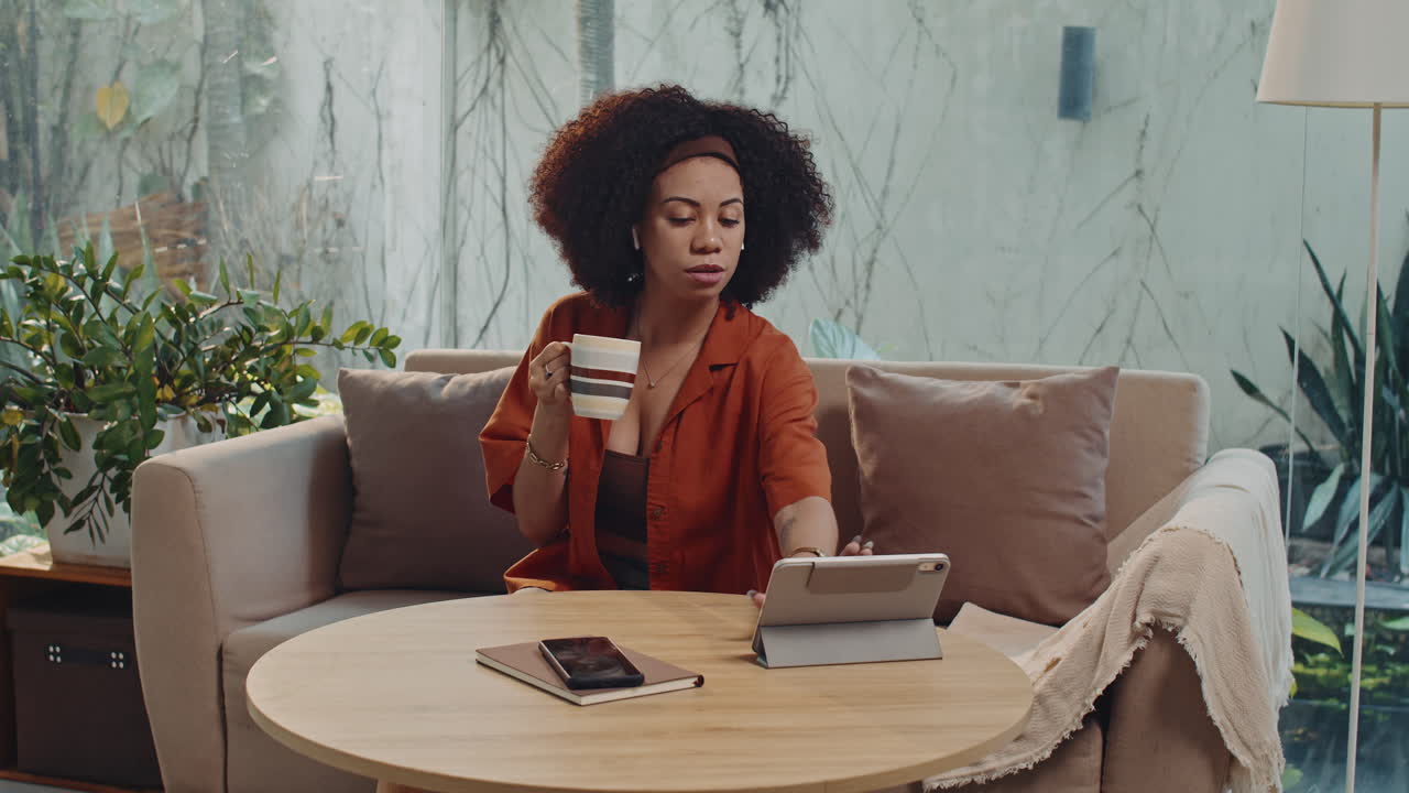 Hispanic Woman Drinking Morning Coffee and Watching Series on Tablet at Home