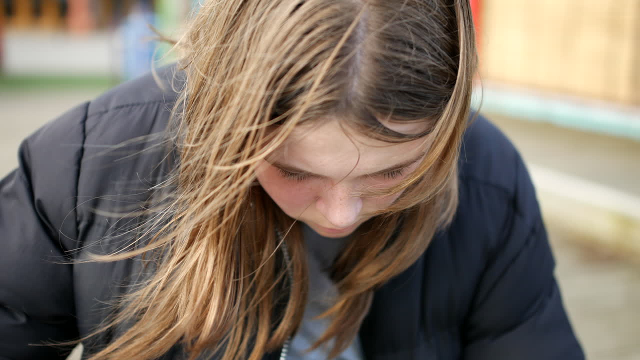 Una ragazza adolescente depressa seduta da sola in una giornata fredda.