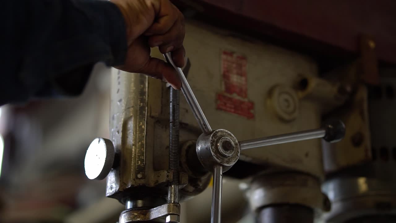 Operaio metallurgico che utilizza un vecchio trapano industriale in un'officina