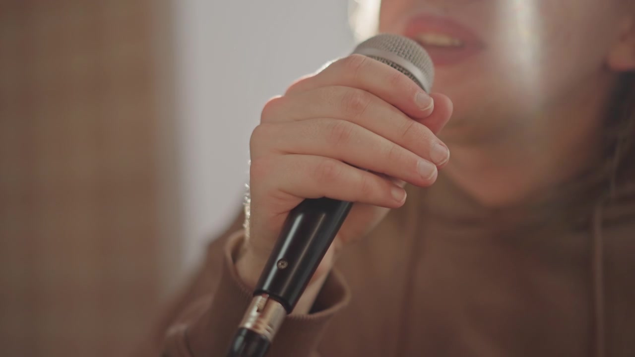 Mic control practice. Detailed image of vocal practice with microphone and hand positioning. Closeup of performer demonstrating breath support and grip techniques during vocal rehearsal