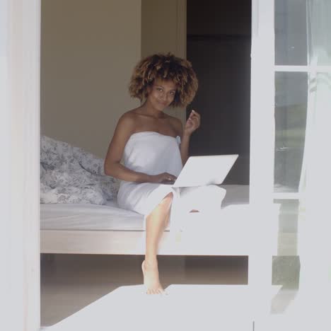 young woman using laptop on bed