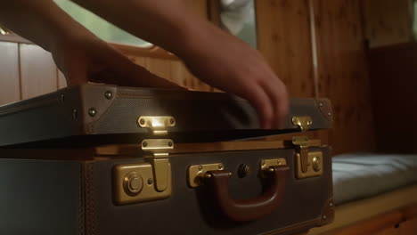hands opening a vintage brown leather suitcase