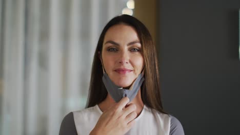 retrato de una mujer caucásica con el cabello liso quitándose la máscara gris
