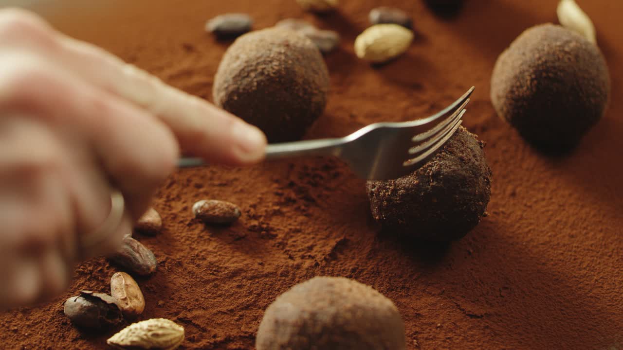 un confitero de primer plano cortando a mano chocolate de trufa con un tenedor en cámara lenta.
