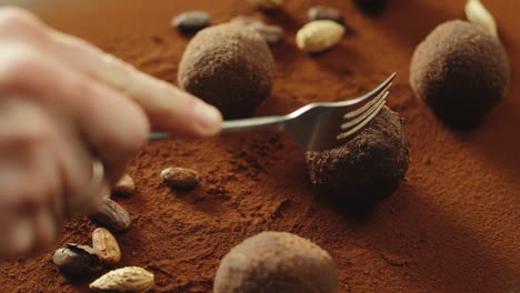 un confitero de primer plano cortando a mano chocolate de trufa con un tenedor en cámara lenta.