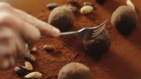 closeup confectioner hand cutting truffle chocolate by fork in slow motion.