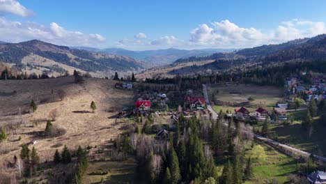 Drone-Pasando-Sobre-Edificios-Construidos-En-La-Naturaleza-Con-Colinas-Y-Bosques-Al-Fondo