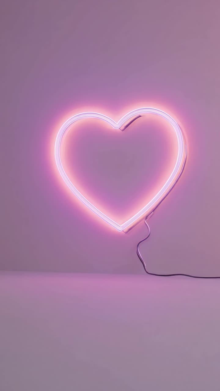A neon heart light glows softly against a pastel pink wall