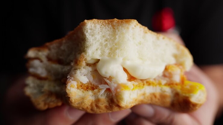 Tasty Fish Burger With Mayonnaise And Cheese On Person's Hand