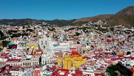 Guanajuato-vibrant-cathedral-colonial-buildings,-Aerial-reverse-panoramic-establishing-dolly