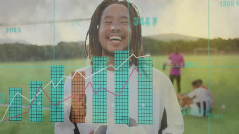 smiling man holding soccer ball with financial data animation over sports field
