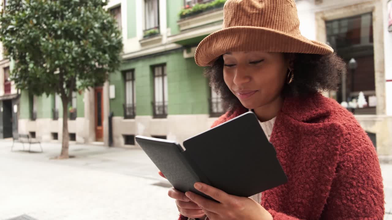 mujer negra leyendo un libro en la ciudad