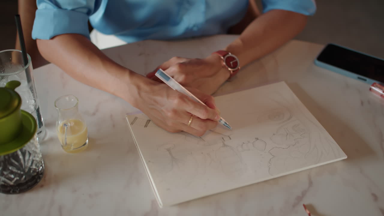 Female Sketcher in Headphones Drawing in Cafe