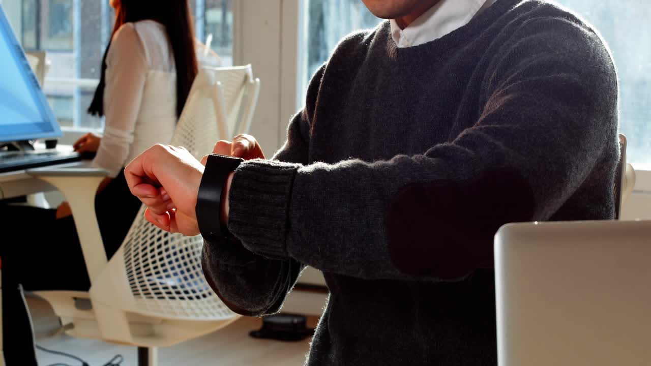 Office worker lifting left wrist and tapping watch, checking messages with chat bubbles multiplying