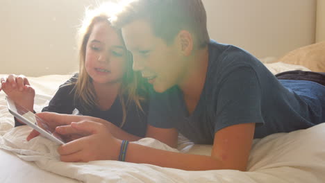 Children-Lying-On-Bed-Using-Digital-Tablet