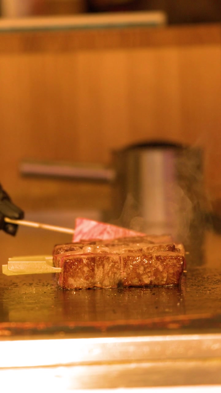 熱い金属製グリルで焼かれ、湯気が立ち上る霜降り牛肉キューブのクローズアップショット