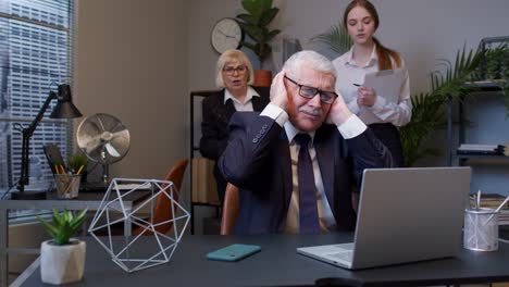 elderly mature freelancer man crosses fingers for good luck prays but losing in office, bankruptcy